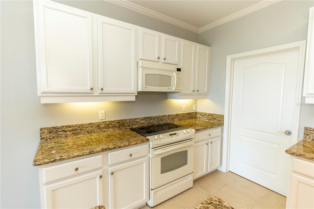 9203 Griggs Road, Unit B102 Englewood, FL 34224 - Photo 11 of 66 a kitchen with granite countertop white cabinets and white appliances