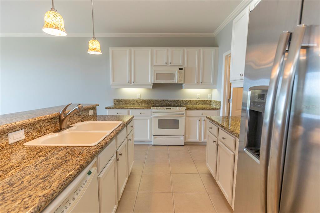 9203 Griggs Road, Unit B102 Englewood, FL 34224 - Photo 14 of 66 a kitchen with granite countertop a sink stove and refrigerator