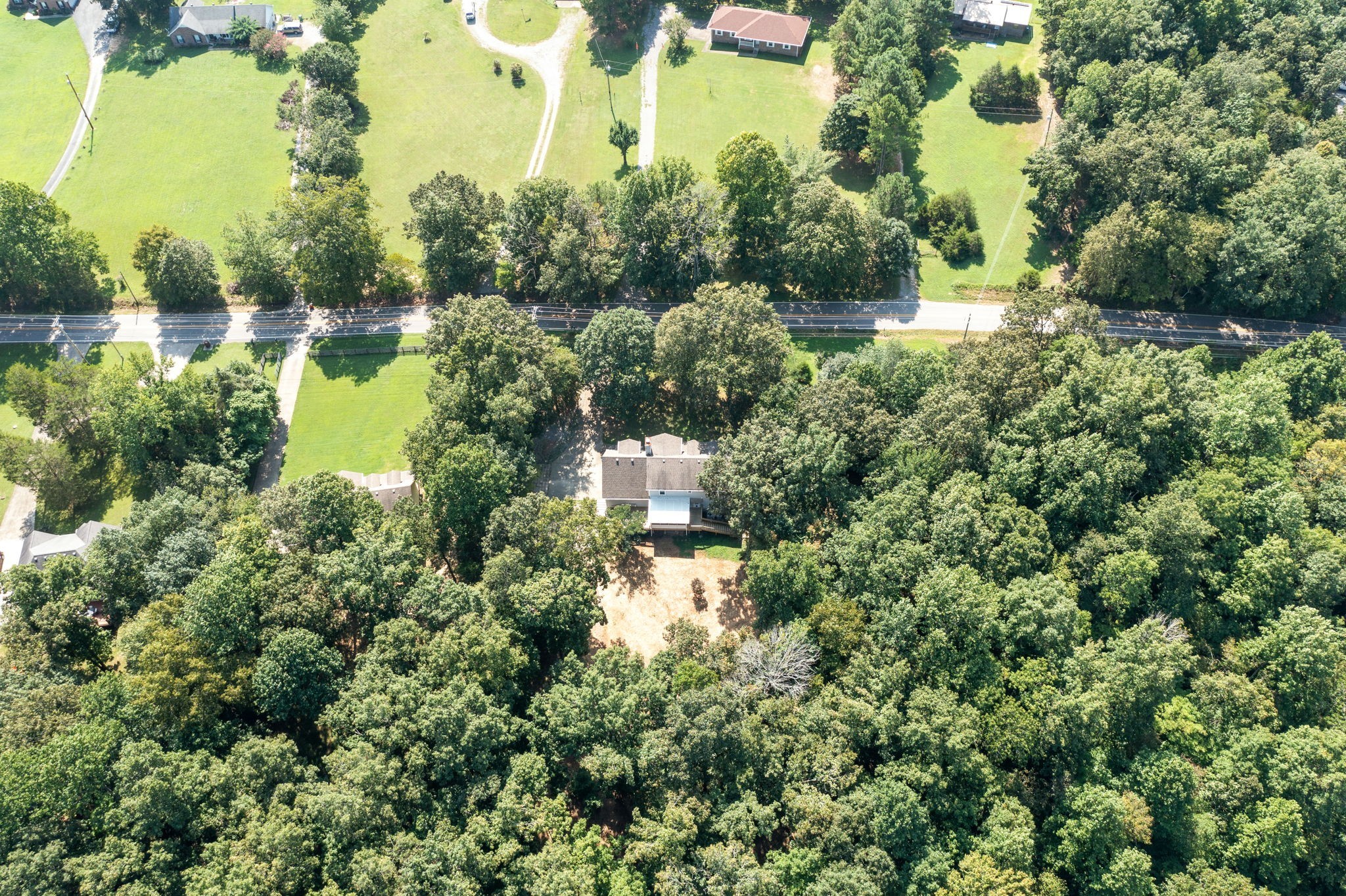 an aerial view of residential houses with outdoor space and trees all around