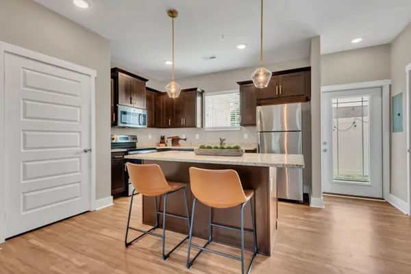 a kitchen with stainless steel appliances granite countertop a refrigerator a stove a sink dishwasher and white cabinets with wooden floor