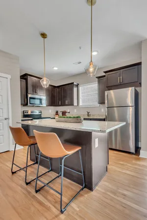 a kitchen with stainless steel appliances granite countertop a refrigerator a sink dishwasher a stove and white cabinets with wooden floor