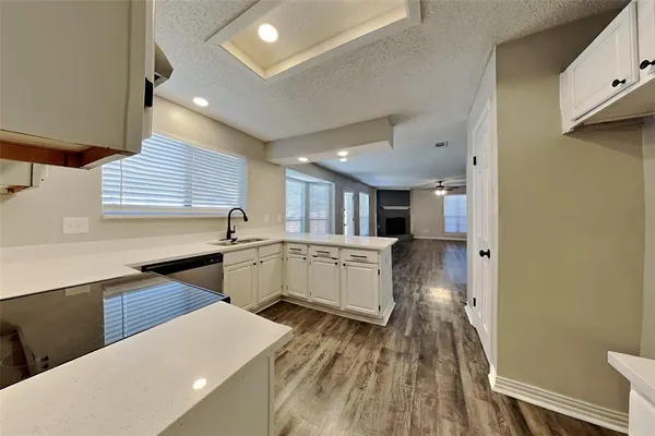 a kitchen with white cabinets and wooden floor