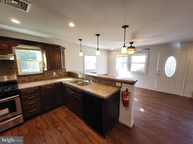 a kitchen with granite countertop a stove a sink wooden floor cabinets and dining table