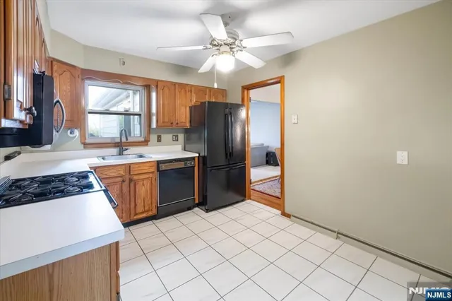 a kitchen with stainless steel appliances a sink a stove a refrigerator cabinets and a dining table