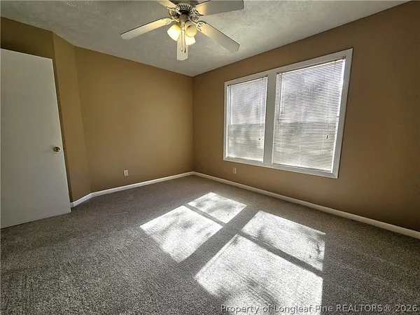 an empty room with a window and a chandelier fan