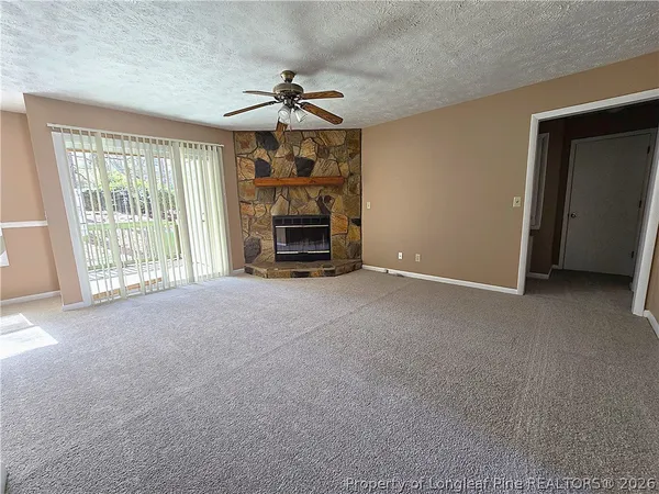 a view of an empty room with a fireplace and a window
