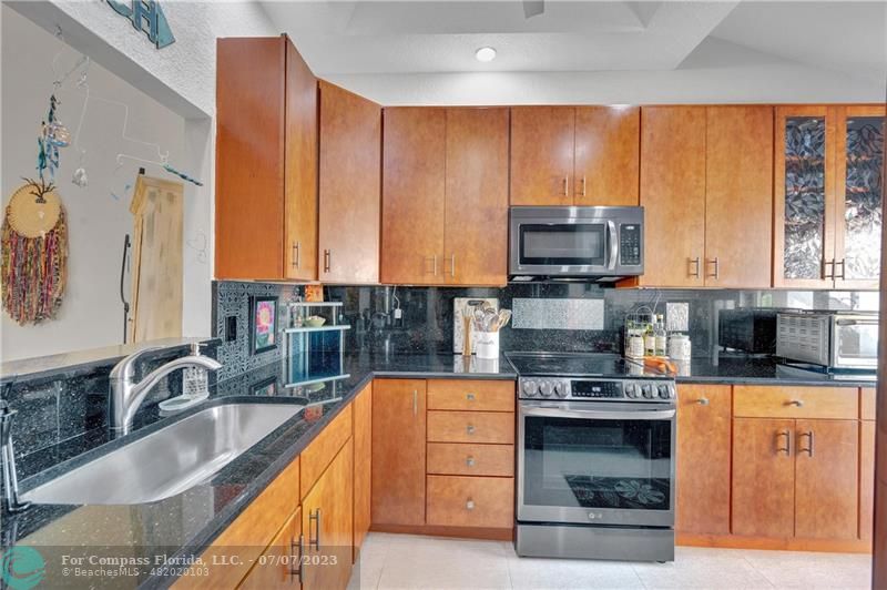 10999 Water Oak Manor Boca Raton, FL 33498 - Photo 14 of 49 a kitchen with stainless steel appliances wooden cabinets a stove and a sink