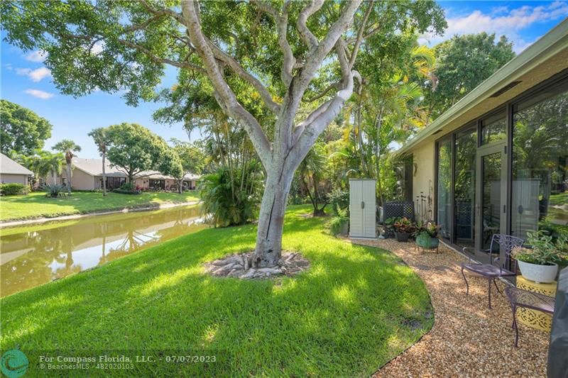 10999 Water Oak Manor Boca Raton, FL 33498 - Photo 42 of 49 a view of a backyard with table and chairs and a large tree