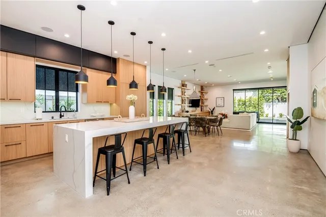 a kitchen with stainless steel appliances granite countertop a stove top oven a sink a dining table and chairs with wooden floor