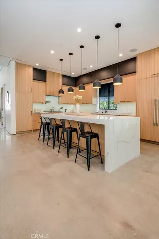 a kitchen with kitchen island a sink a stove a dining table and chairs