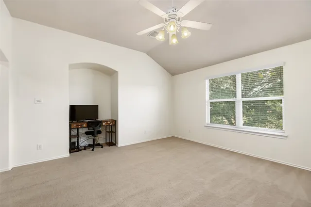 an empty room with windows and fan chandelier