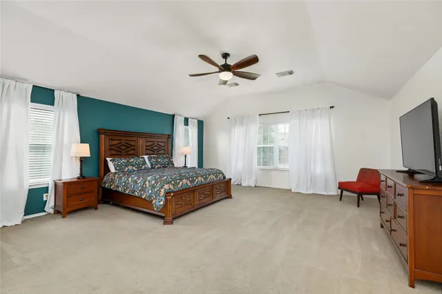 a bedroom with a bed chair and a flat screen television