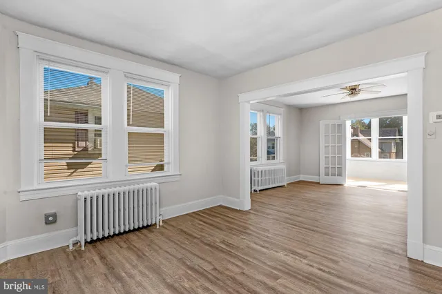 a view of an empty room with wooden floor and windows