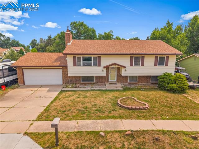 1921 Wooten Road Colorado Springs, CO 80915 - Photo 37 of 49 Bi-level home with a front yard, a garage, a chimney, brick siding, and driveway