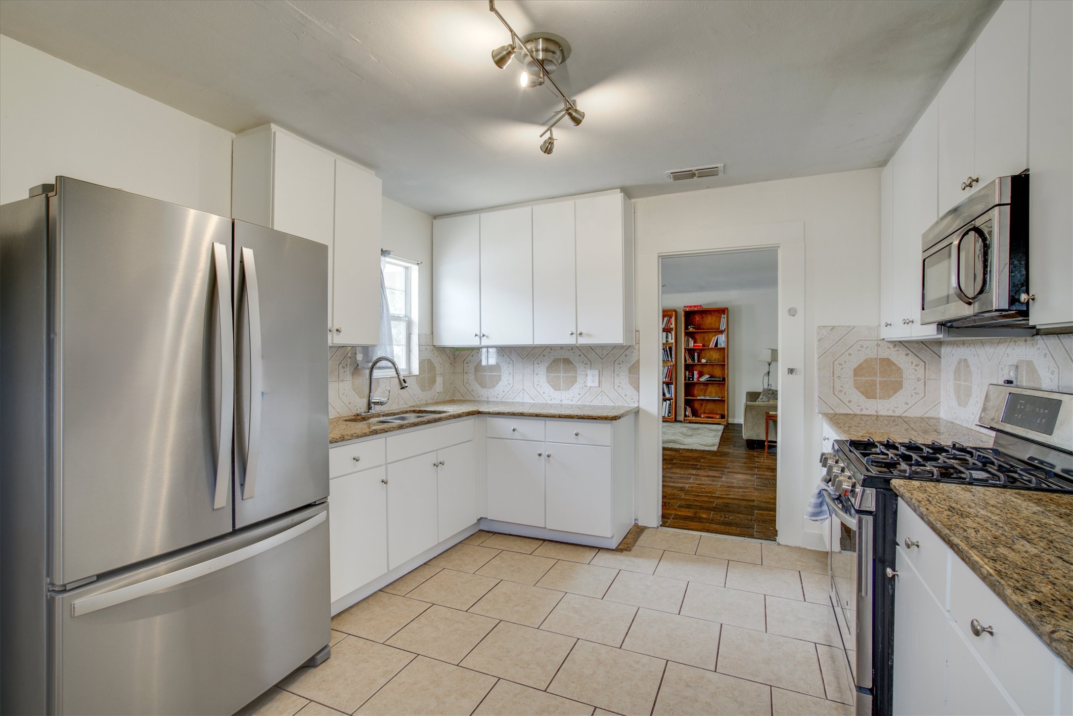 4615 Ribbecke Avenue Austin, TX 78721 - Photo 1 of 19 Kitchen featuring stainless steel appliances, light stone countertops, white cabinets, and light tile patterned floors