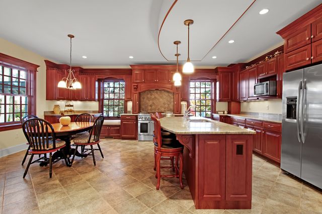 a kitchen with stainless steel appliances kitchen island granite countertop a table chairs and a refrigerator