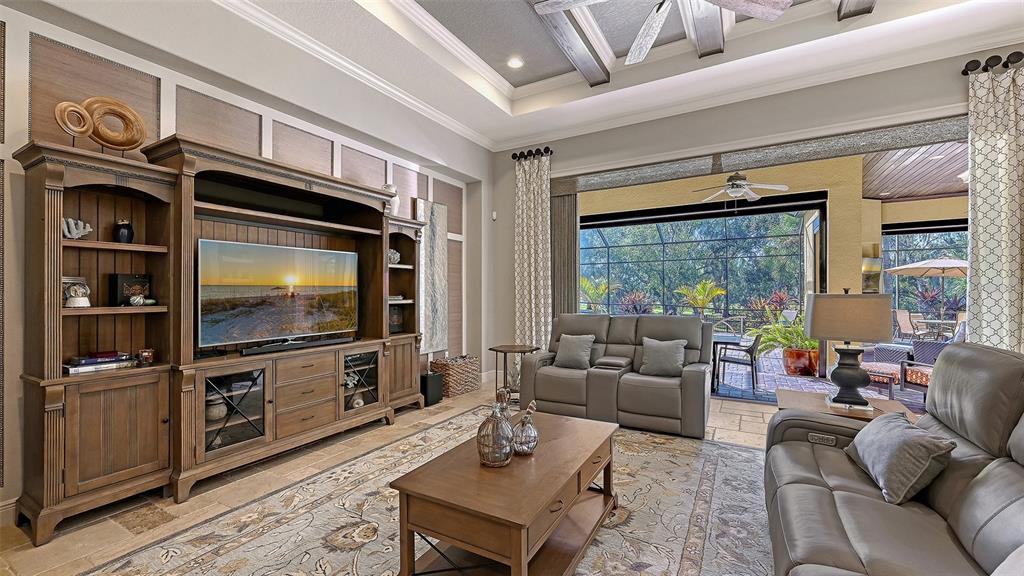 9489 Swaying Branch Road Sarasota, FL 34241 - Photo 8 of 37 a living room with furniture a flat screen tv and a floor to ceiling window