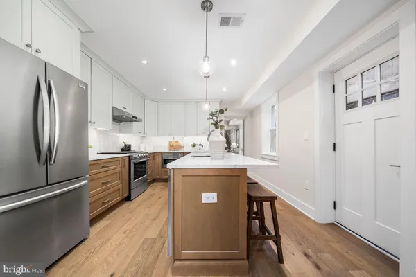a kitchen with kitchen island a counter top space a sink stainless steel appliances and cabinets