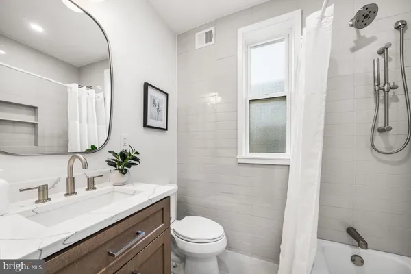 a bathroom with a granite countertop sink toilet a mirror and shower