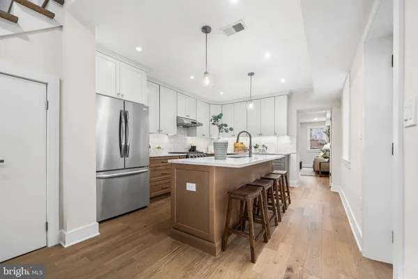 a kitchen with stainless steel appliances granite countertop a refrigerator a sink dishwasher a stove and a refrigerator with wooden floor