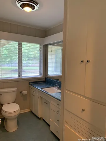 a bathroom with a granite countertop toilet a sink and window