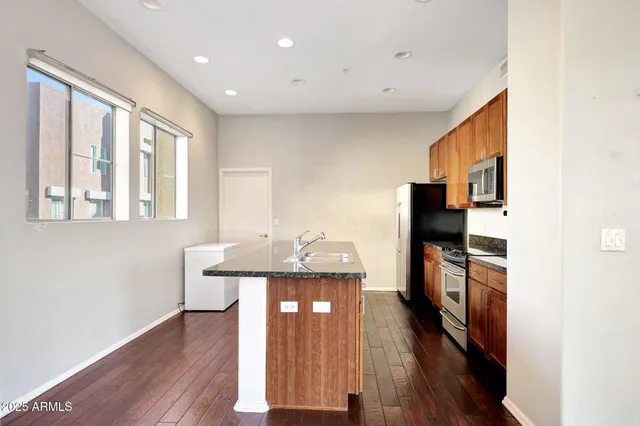 a view of a house with kitchen island stainless steel appliances wooden floor and wooden cabinets