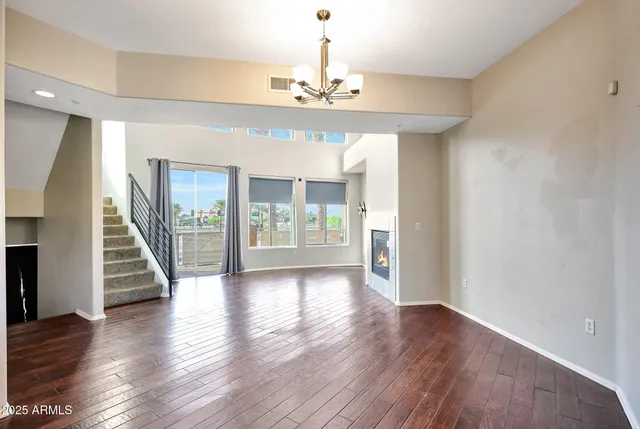 an empty room with wooden floor chandelier and windows