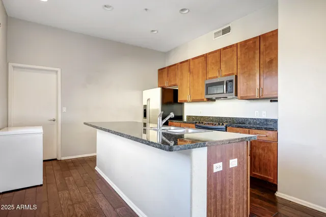 a kitchen with stainless steel appliances granite countertop a stove a sink and a refrigerator