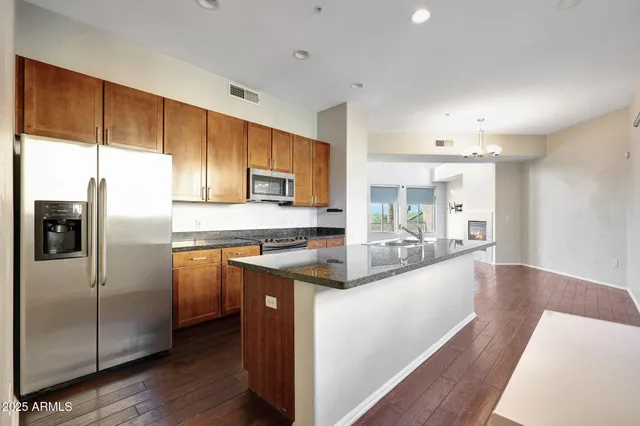 a kitchen with stainless steel appliances granite countertop a refrigerator a sink a stove and cabinets