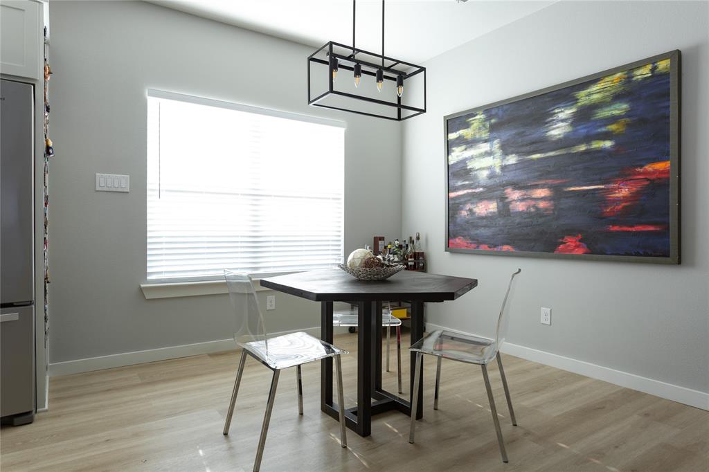 1108 Claude Street Dallas, TX 75203 - Photo 9 of 17 Dining area featuring wood-finish flooring, a large window with blinds, and a contemporary linear chandelier