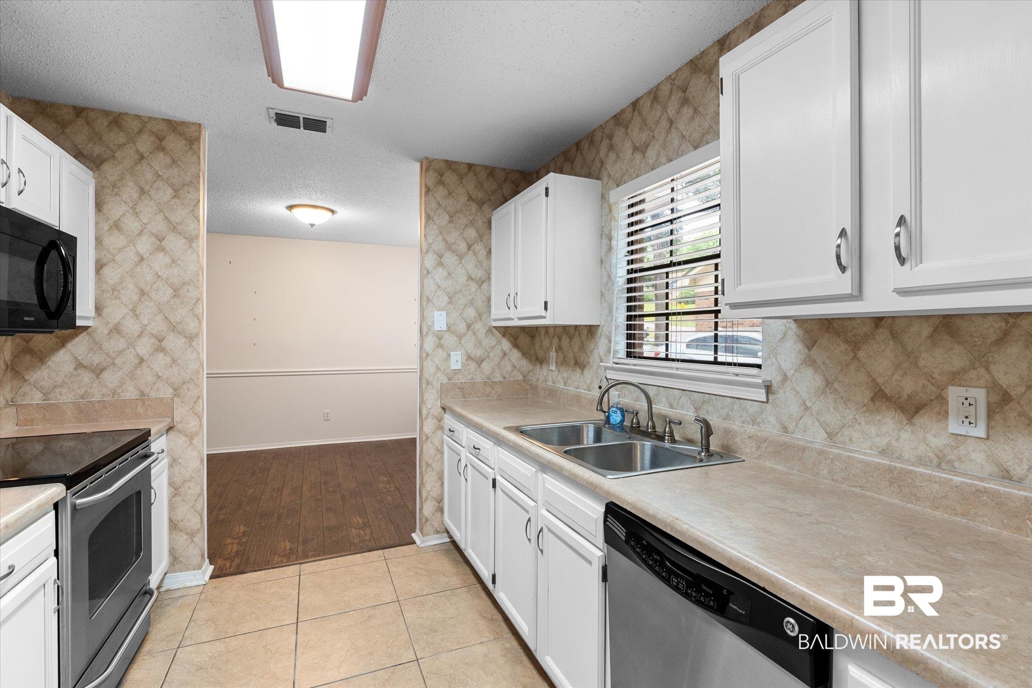 5645 Green Tree Road Mobile, AL 36609 - Photo 7 of 30 Kitchen with stainless steel appliances, a sink, white cabinetry, light countertops, and a textured ceiling