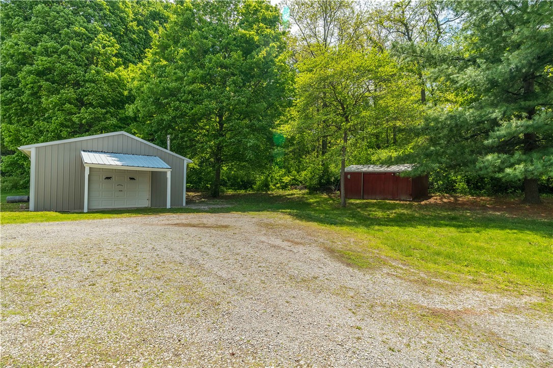 1319 Perry Road Cable, OH 43009 - Photo 31 of 44 This property offers a spacious gravel driveway leading to a garage and an additional shed.
