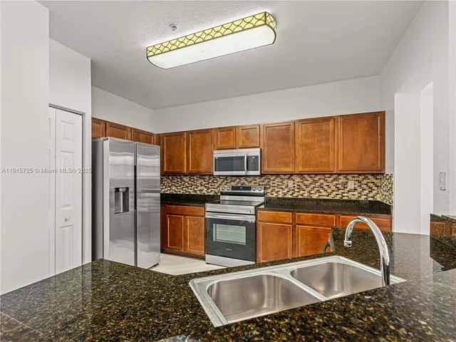 a kitchen with stainless steel appliances granite countertop a sink stove and refrigerator
