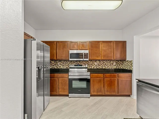 a kitchen with stainless steel appliances granite countertop a stove and a refrigerator