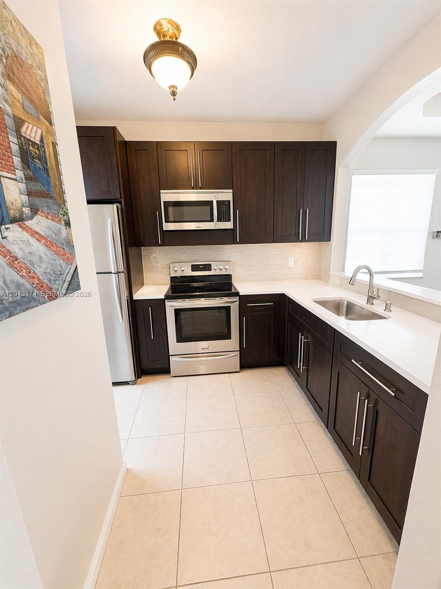 993 Northeast 3rd Avenue Homestead, FL 33030 - Photo 4 of 16 a kitchen with stainless steel appliances granite countertop a sink and stove top oven
