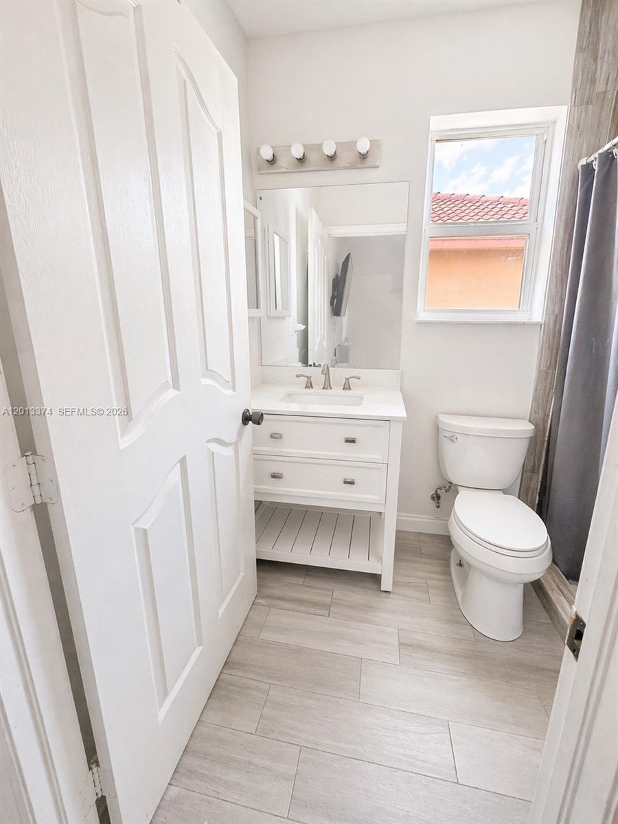 993 Northeast 3rd Avenue Homestead, FL 33030 - Photo 6 of 16 a bathroom with a sink a toilet and a mirror