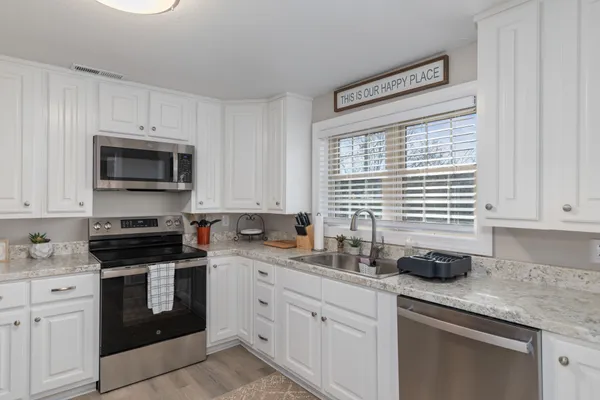 a kitchen with granite countertop white cabinets white appliances and a sink