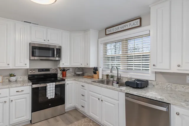 a kitchen with granite countertop white cabinets white appliances and a sink
