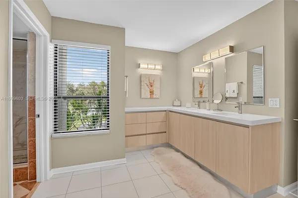 a large white bathroom with a double vanity sink a mirror a window and a bathtub