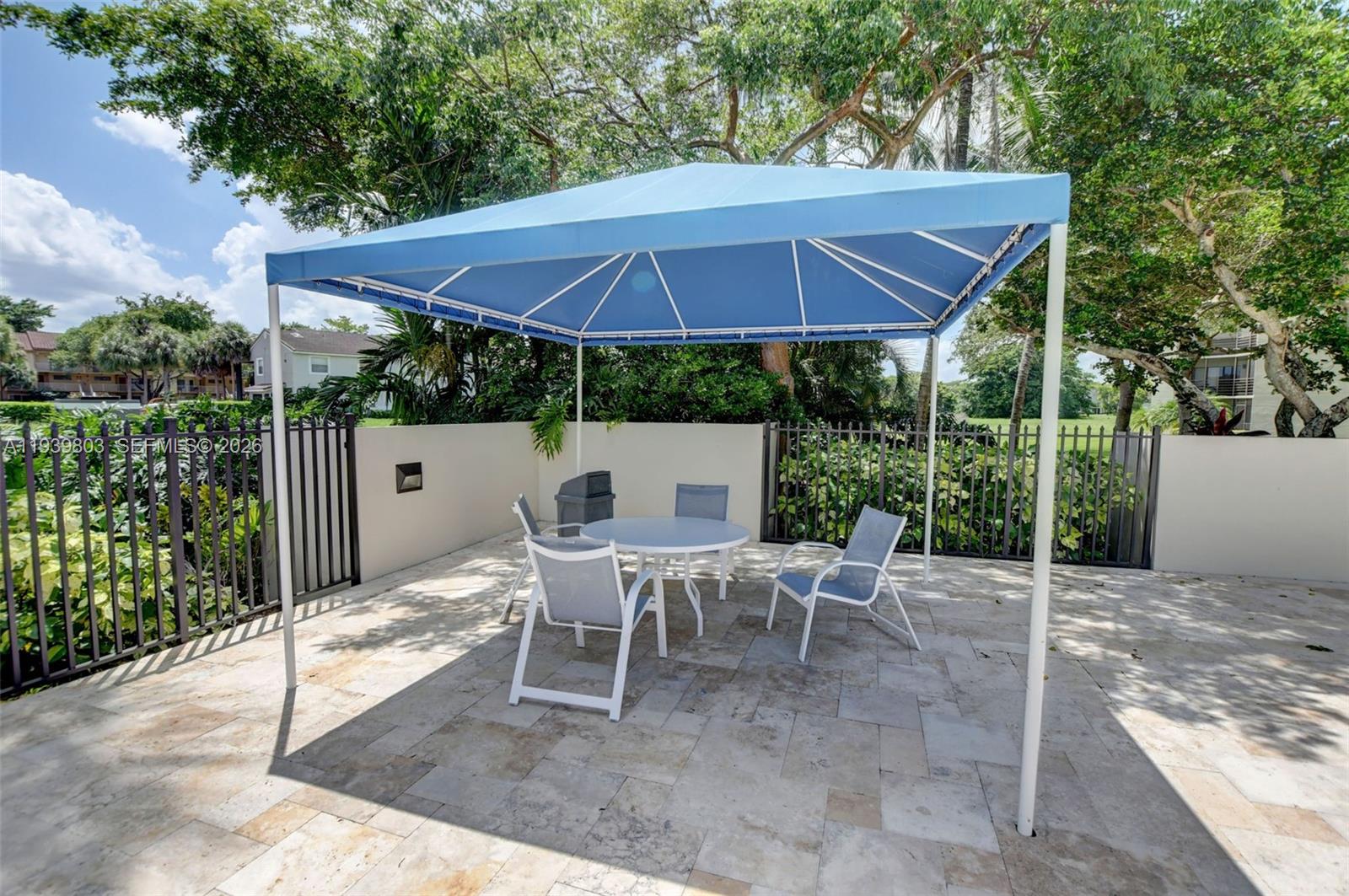 5901 Camino Del Sol, Unit 207 Boca Raton, FL 33433 - Photo 43 of 53 a view of a patio with a table and chairs under an umbrella