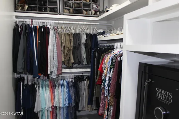 a view of walk in closet with clothes and shoes