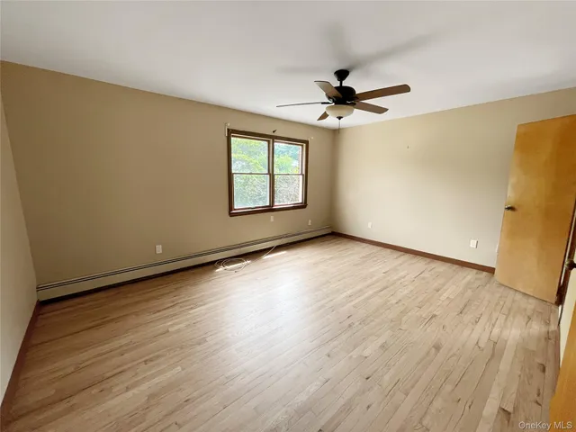 an empty room with wooden floor fan and windows