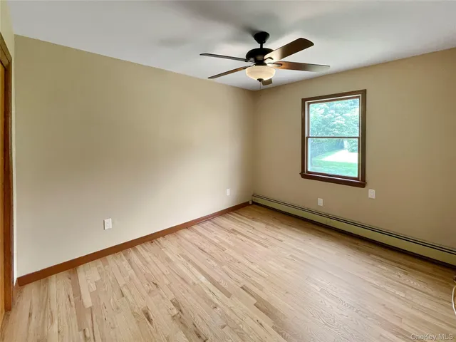 a view of an empty room with a window and wooden floor