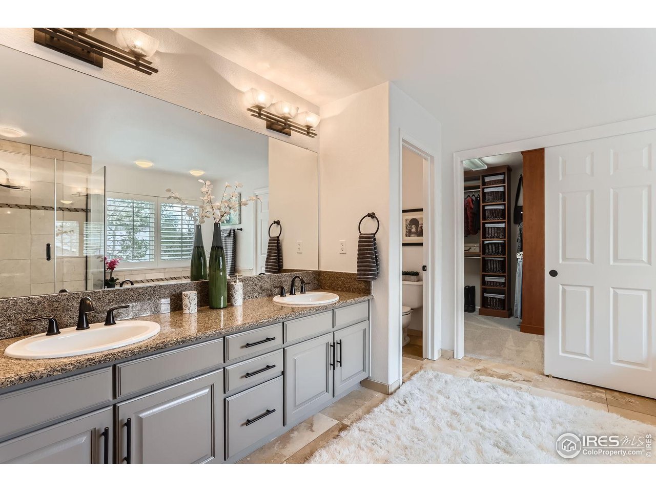 1069 Monarch Way Superior, CO 80027 - Photo 18 of 40 a bathroom with a double vanity sink a large mirror and a shower