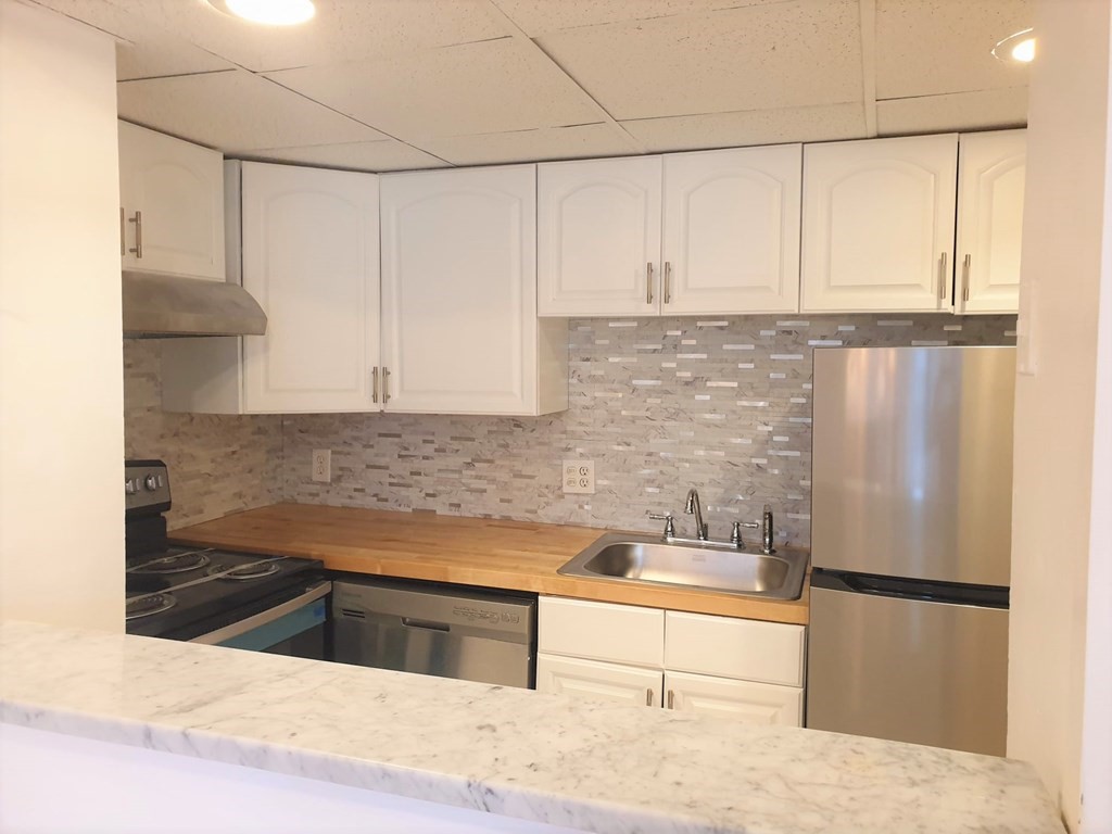 466 Commonwealth Avenue, Unit 302 Boston, MA 02215 - Photo 1 of 12 a kitchen with granite countertop a refrigerator sink and cabinets