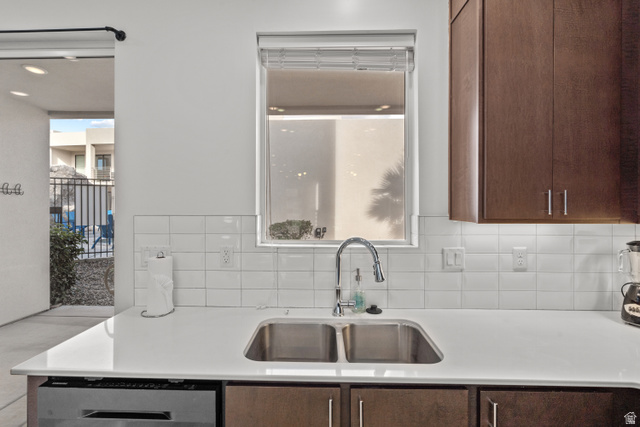 1122 South 1790th West, Unit 1 St. George, UT 84770 - Photo 9 of 37 Kitchen featuring a stainless steel double basin sink with a gooseneck faucet, white subway tile backsplash, light-toned countertop, and dark wood-finish cabinetry