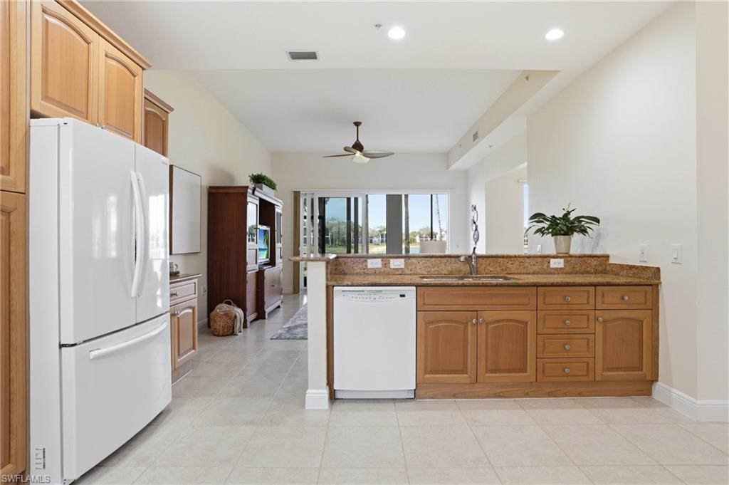 9263 Museo Circle, Unit 103 Naples, FL 34114 - Photo 8 of 49 Kitchen featuring white appliances, dark stone counters, a peninsula, wood finish cabinets, and a ceiling fan
