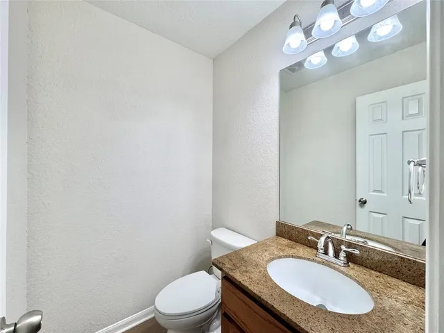 a bathroom with a granite countertop sink a toilet and a mirror