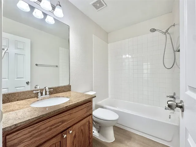 a bathroom with a granite countertop sink a toilet and shower