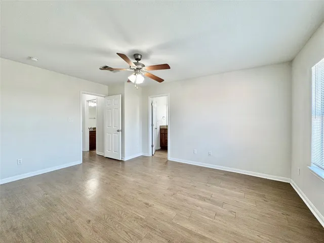 an empty room with wooden floor and a ceiling fan